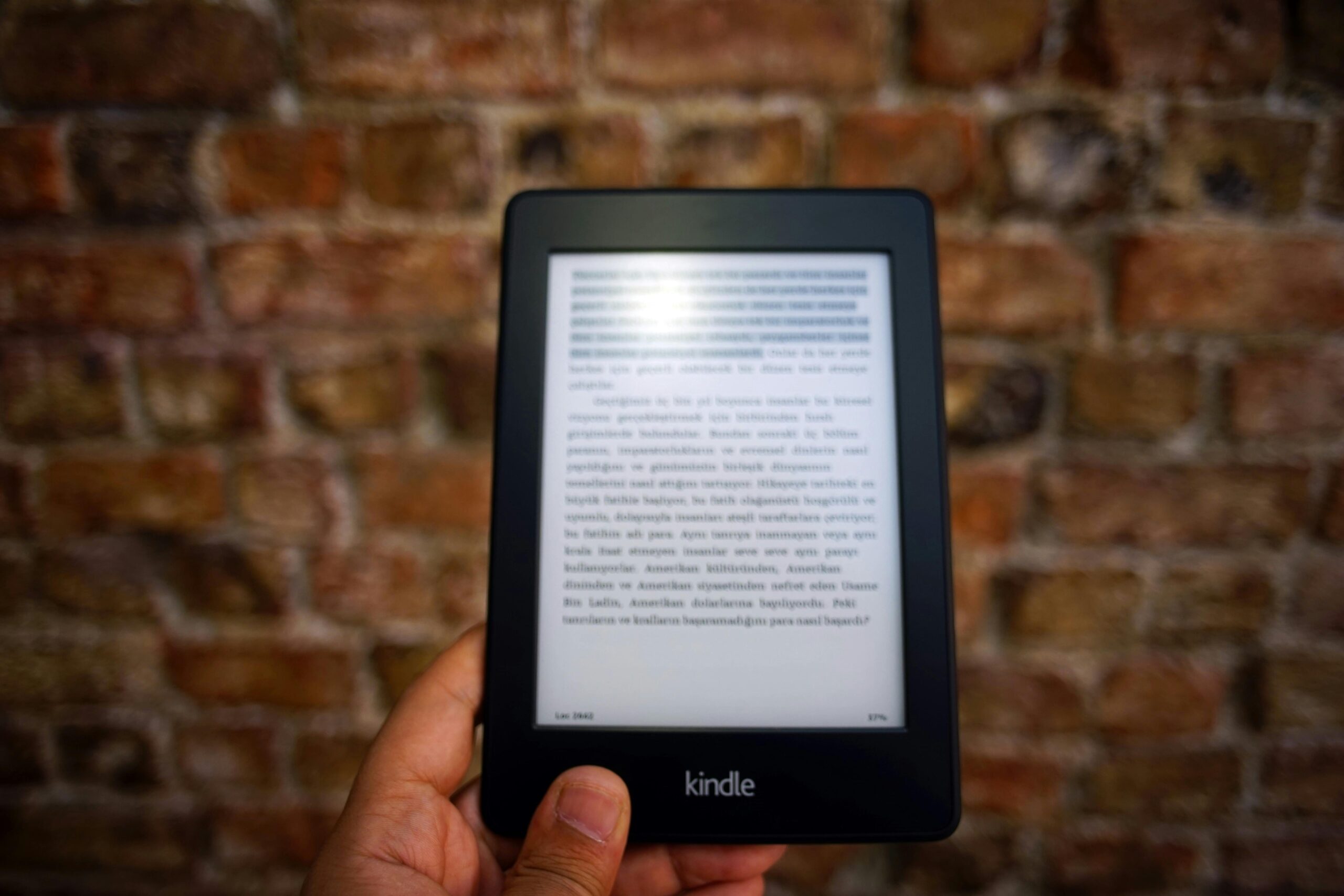 pexels photo 844734 844734 Close-up of a Kindle e-reader held by a person, showcasing a digital reading device against a textured brick wall backdrop.